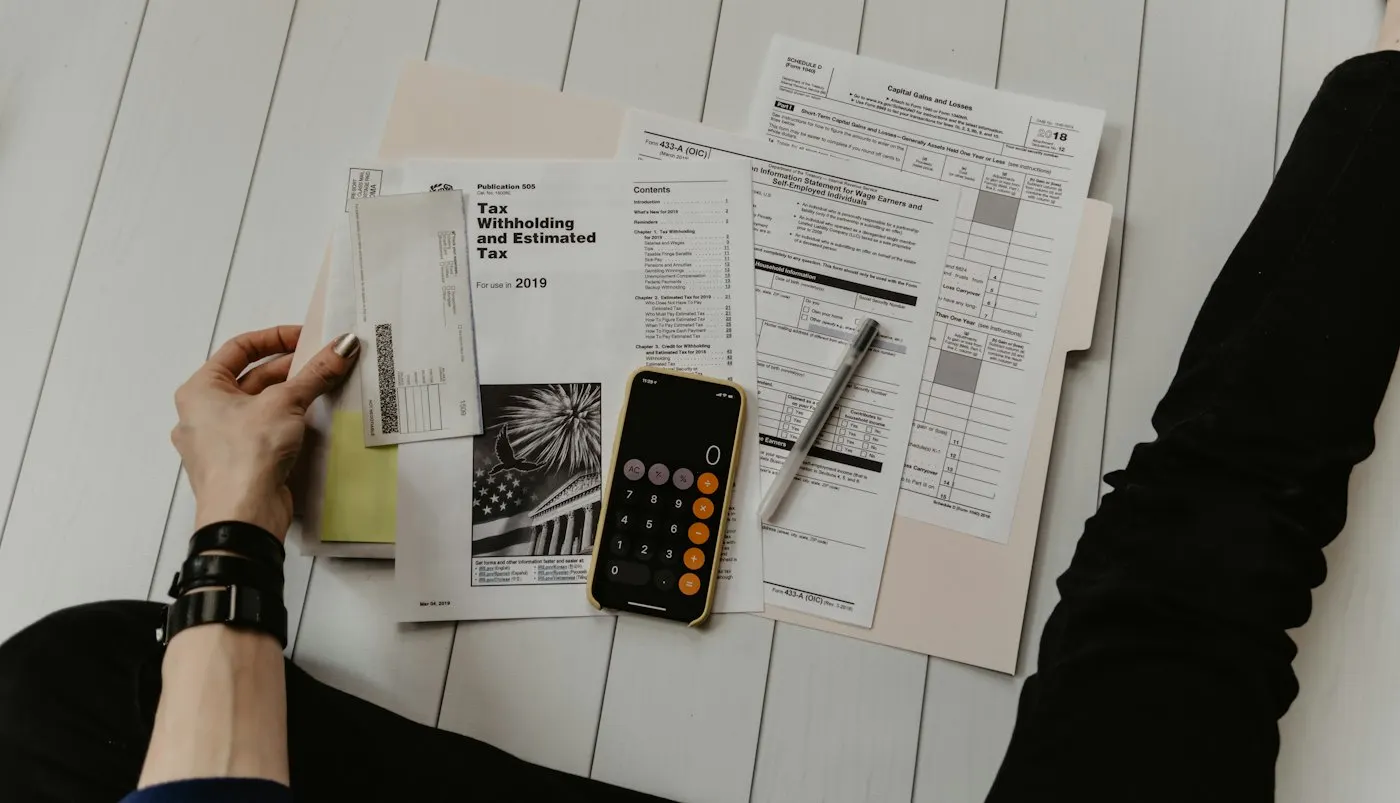 A desk with a calculator, notebook and household financial documents laid out for a family budget review